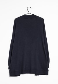 Suéter oversize de un oscuro color navy con cuello acanalado, mangas largas y un dobladillo ligeramente curvado. Hecho de tela de punto, colgando de un gancho negro.