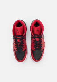 Een paar rood en zwart hoge Air Jordan sneakers met zwarte veters, gezien van bovenaf op een witte achtergrond.