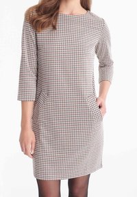 Rutigt kort klänning med trekvartslånga ärmar, som har fickor, i nyanser av kräm, röd och blå på en texturerad tyg.