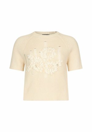 Pull en maille à manches courtes couleur crème avec texture côtelée et broderie florale présentant des pétales et des feuilles en relief sur le devant.