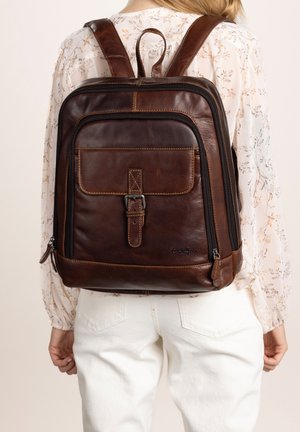 Brown leather backpack with adjustable straps, front pocket, and zipper closures. Features stitching details and a loop handle on top.