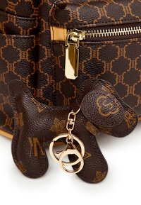 Borsa a mano in pelle marrone con motivo a monogramma, dotata di una cerniera dorata e un portachiavi a forma di cane realizzato in materiale e colore abbinati.