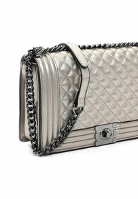 Bolso de mano plateado metálico acolchado con cadena, de forma rectangular, textura suave y detalle de cierre de hardware plateado.