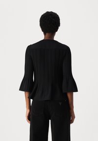 Schwarze Bluse mit gefaltetem Design, glockenförmigen Ärmeln und rundem Ausschnitt. Der Stoff wirkt glatt mit einem dezenten Glanz.