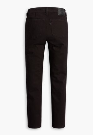 Schwarze Slim-Fit-Jeans, von hinten gezeigt, mit zwei Gesäßtaschen und einem Leder-Brandpatch am Bund.