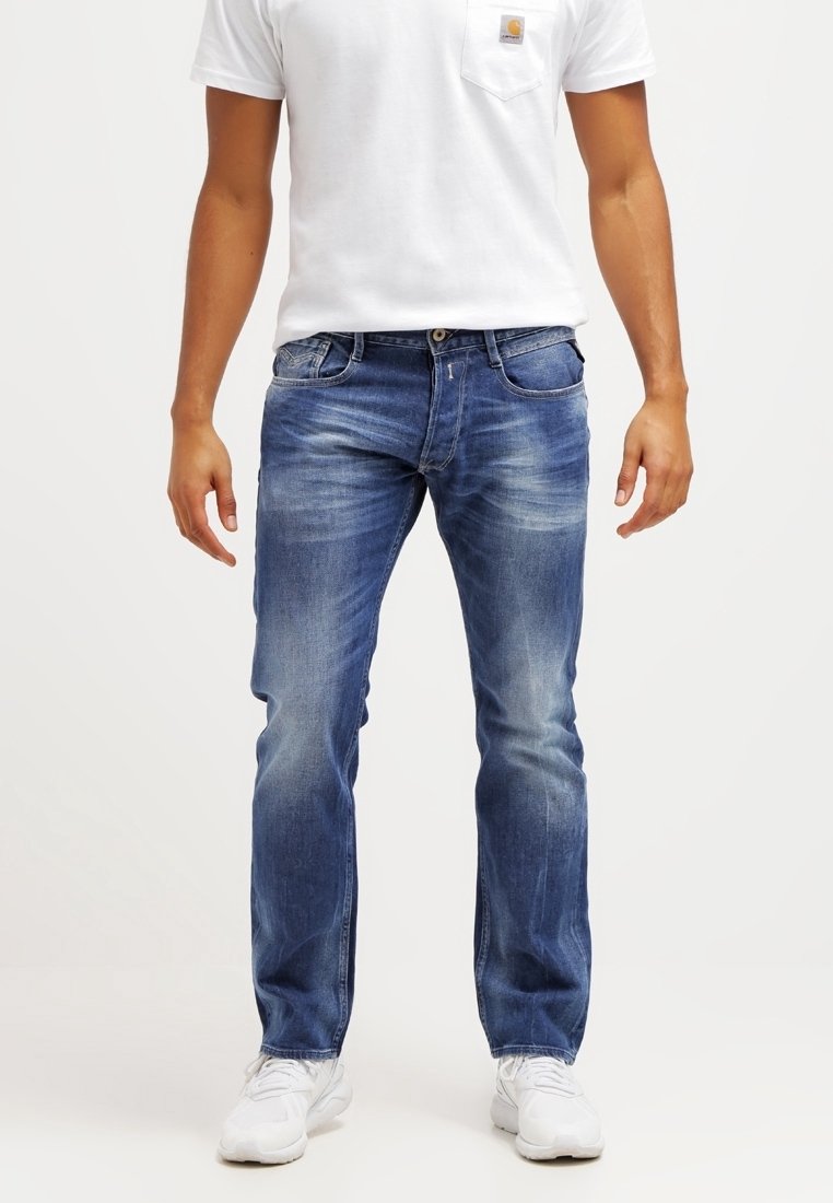Blå denimjeans med rak skärning, ljus blekning, fem fickor och sömnadsdetaljer. Bärs med en vit t-shirt och vita sneakers.