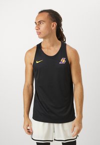 Fekete kosárlabda mez lélegző hálós anyagból. Sárga Nike logóval és lila csapatlogóval a bal mellkason.