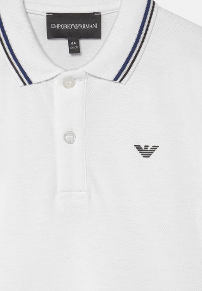 Polo shirt branco feito de tecido texturizado, apresentando um fechamento com três botões, colarinho listrado em preto e azul marinho, e um logótipo bordado.