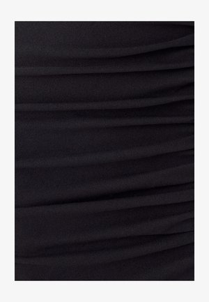 Vêtement noir en tissu doux et extensible avec une texture froncée ; un subtil éclat ajoute de la profondeur au design de surface.