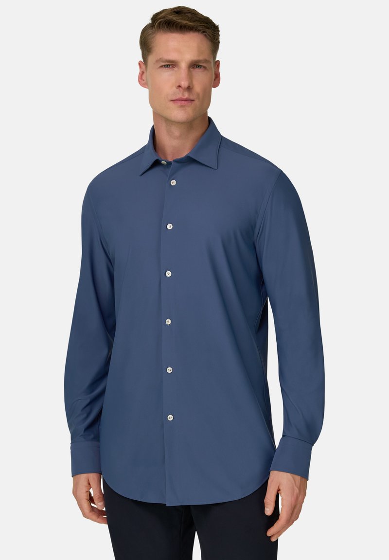 Chemise à manches longues boutonnée en bleu marine, en tissu lisse. Elle présente un col, des boutons sur le devant et un ourlet arrondi.