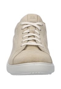 Beige semišové tenisky s bílými tkaničkami, zaoblenou špičkou a jemným bočním prošíváním. Mají bílou gumovou podrážku a embosované logo na jazyku.