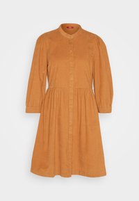 Robe en velours côtelé orange rouille à manches longues, boutonnée sur le devant, avec taille froncée et col rond sur fond clair uni.