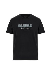 Camiseta de algodón negra con cuello redondo, mangas cortas y texto gráfico en la parte frontal "GUESS EST. 1981" en franjas blancas y azul claro.
