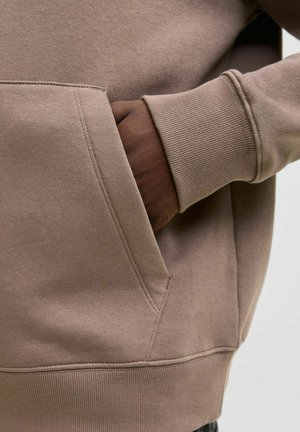 Brauner Pullover mit Tasche vorne und gerippten Bündchen. Weicher, strukturierter Stoff mit sichtbaren Steppnähten.