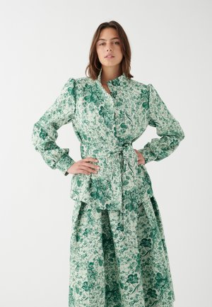 Grünes Blusen- und Rockset mit floralem Muster. Die Bluse hat einen hohen Ausschnitt, Puffärmel und eine gebundene Taille. Das Material hat eine leichte Textur.