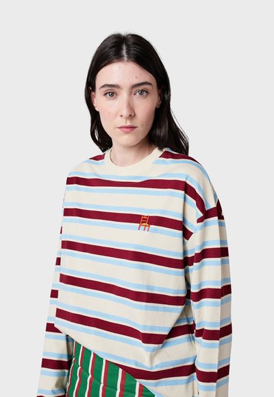 Koszula z długim rękawem w paski w kolorze kremowym, czerwonym i niebieskim. Posiada małe haftowane logo krzesła. Miękka tkanina o luźnym kroju i szerokim dekolcie.