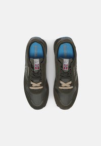 Scarpe sportive di colore verde scuro con una tomaia in rete e suede, dotate di lacci beige, solette blu e etichette con il logo sulla linguetta.