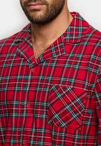 Rot kariertes Schlafshirt mit grünen und weißen Akzenten, ausgestattet mit einem Kragen, Knöpfen und einer aufgesetzten Tasche auf der linken Seite. Aus Baumwollmaterial.