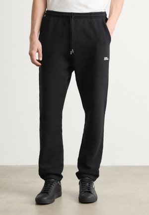 Pantalons de survêtement noirs en tissu doux, dotés d'une taille élastique avec cordon de serrage, d'une finition à l'ourlet et d'un petit logo blanc sur le côté.