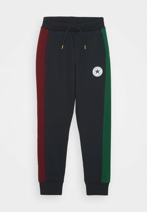 Czarne spodnie dresowe z ciemnoczerwoną paskiem po lewej stronie, ciemnozieloną paskiem po prawej stronie, ściągaczem w pasie i białym logo Converse All Star na prawej uda.