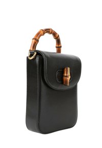 Sac à main en cuir noir avec poignée en bambou courbée et fermoir en bambou sur le rabat avant, présenté sur fond blanc.