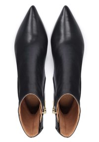 Botas de tobillo de cuero negro con punta afilada, cremalleras laterales y textura suave. El interior es color caramelo con costuras visibles.