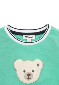 Groene katoenen t-shirt met een zachte witte berenapplicatie aan de voorkant, afgewerkt met een geribde kraag in zwart en wit. Label zichtbaar aan de binnenzijde.