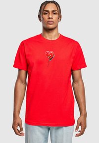 Rød kortærmet T-shirt lavet af bomuld, med et hjerteformet ballon-design med et blomstermønster på brystområdet.