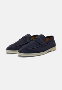 Mocassini in suede blu navy con una texture liscia, punta rotonda, suola in gomma leggera a contrasto e una fascia decorativa sulla parte anteriore.