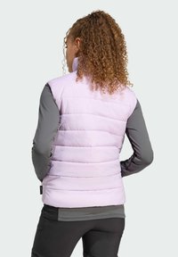 Hellviolette Steppweste mit horizontalem Steppdesign, hohem Kragen und grauen langen Ärmeln, getragen über einem schwarzen, enganliegenden Oberteil.