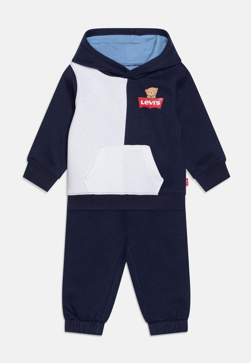 Navy and white two-piece tracksuit featuring a hooded sweatshirt with a bear logo, front pocket, and elastic waistband pants.