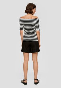 Zwart-wit gestreepte off-shoulder top met korte mouwen, gecombineerd met zwarte shorts en zwarte sandalen. Gladde stof, strakke pasvorm.