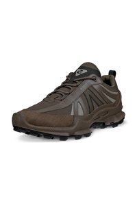 Brown athletic shoe with textured mesh upper and synthetic accents. Features a cushioned sole and rugged tread for grip. Logo on tongue.