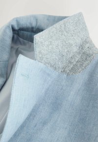 Collar and upper section of a light blue jacket with a contrasting soft gray inner collar lining.