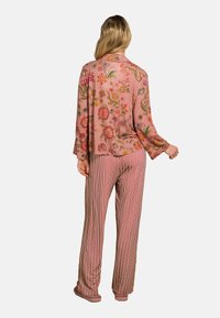 Floral patterned pink blouse with long sleeves paired with striped wide-leg pants in muted tones, featuring a relaxed fit and soft texture.