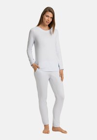 Světle modrý loungewear set vyrobený z hladké tkaniny, obsahující top s dlouhým rukávem a kulatým výstřihem a přiléhavé kalhoty s elastickými manžetami.