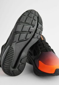 Black and orange athletic shoes with a textured sole, gradient upper, and prominent lacing system. Features a durable design for support.