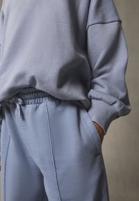 Sweat-shirt oversize bleu clair avec poignets côtelés, assorti à un pantalon de survêtement avec une taille élastique et des poches latérales.