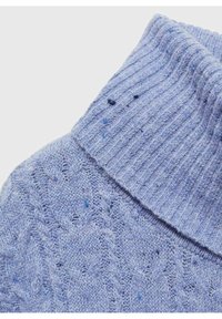 Suéter azul claro con cuello alto acanalado y un patrón tejido texturizado, con pequeñas motas de azul más oscuro a lo largo.