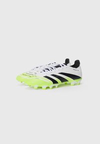 Football boots featuring a white upper with textured patterns, black stripes, and a bright neon green sole and accents.