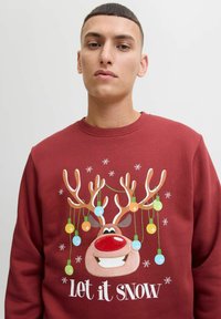 Rode sweatshirt met een rendierafbeelding, waarvan de hoorns zijn versierd met kleurrijke lichtjes, en de tekst "Laat het sneeuwen" in het wit.