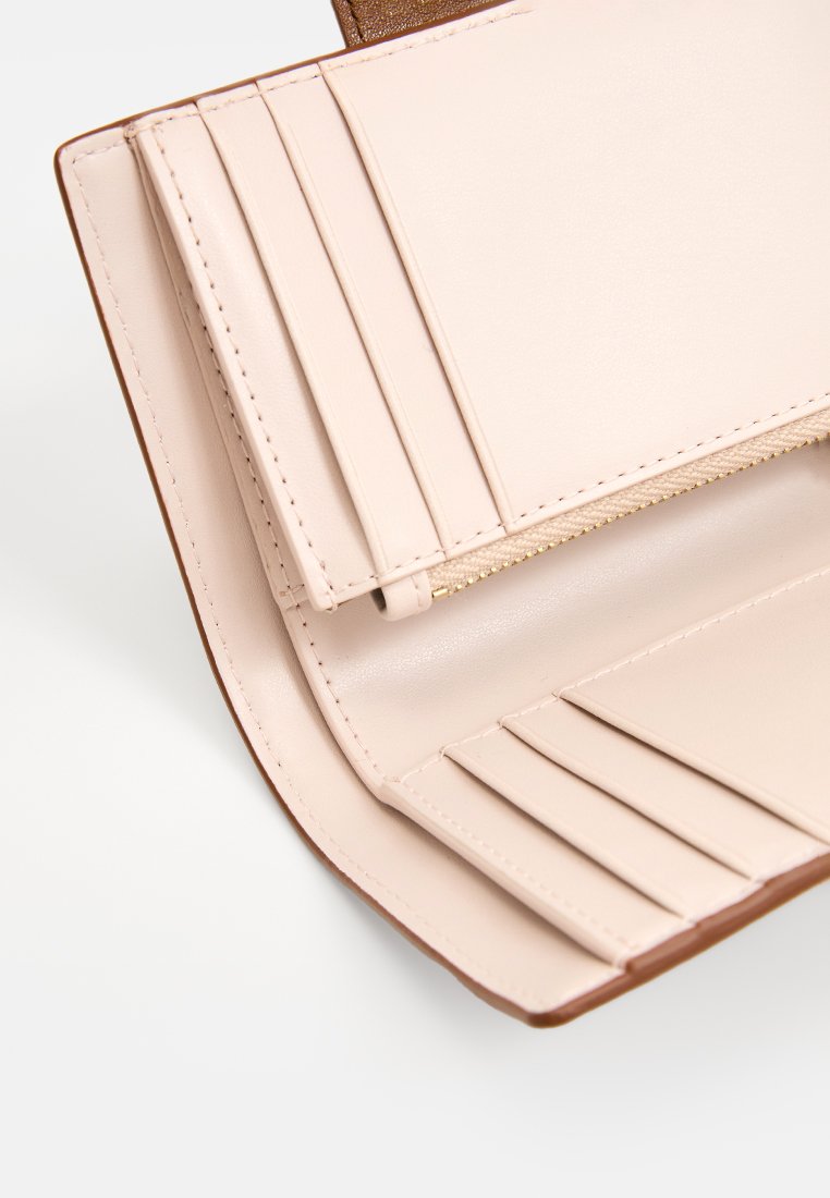 Porte-monnaie en cuir rose clair avec plusieurs emplacements pour cartes et un compartiment zippé, présentant une texture lisse et un bord extérieur marron.
