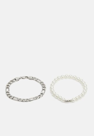 Vasara sidabro grandinėlė kairėje, su pailgomis jungtimis; perlų apyrankė dešinėje, sudaryta iš apvalių baltų karoliukų su sidabro akcentu.