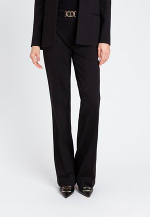 Pantaloni neri su misura con una vestibilità dritta, realizzati in tessuto morbido, arricchiti da una elegante fibbia dorata e scarpe nere a punta.