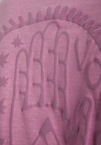 Kortærmet pink stof med et tekstureret grafisk design, der viser en hånd og stjerner. Subtil tonemæssig variation og glat tekstur.