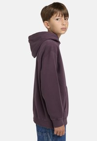 Diepe paarse hoodie van een katoenmengsel. Heeft verlaagde schouders, een kangoeroezak aan de voorkant en ribgebreide cuffs. Eenvoudig ontwerp zonder patronen.