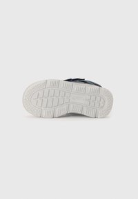 Sneakersåle med strukturert hvit gummi, som har et rutenettmønster for grep. Kanten er svakt avrundet, med rene linjer og ingen synlige logoer.