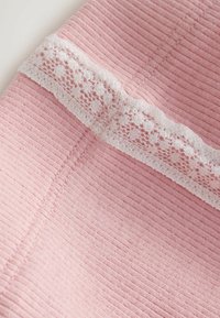 Tela rosa suave con canaletas y una banda horizontal de encaje blanco con un patrón floral cosida sobre la superficie.