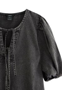 Sort denim bluse med puffede ærmer og knytning ved halsudskæringen, som viser tekstureret stof og kontraststing detaljer.