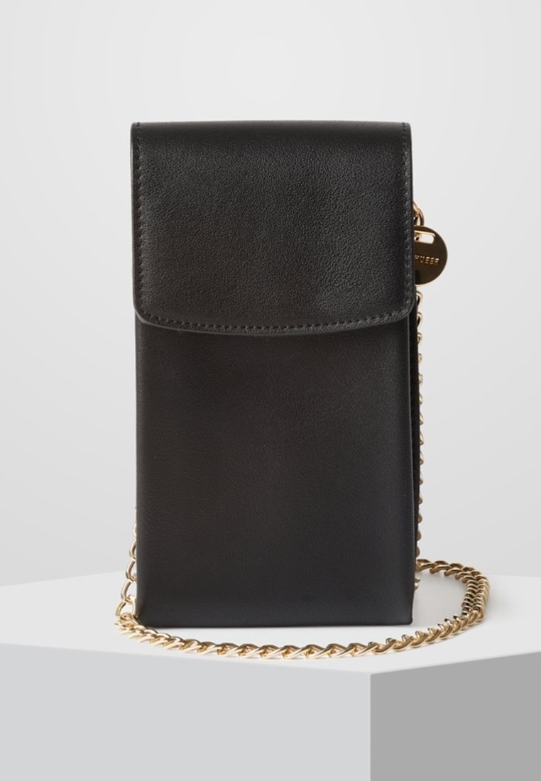 Černá kožená kabelka přes rameno s klopou, zlatým řetízkovým popruhem a hladkou texturou. Má připevněný malý zlatý štítek pro detail.